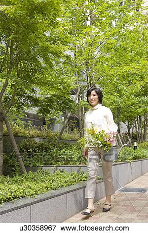 A woman walking and carrying Flowers View Large Photo Image Stock Photo - A woman walking and carrying Flowers. Fotosearch