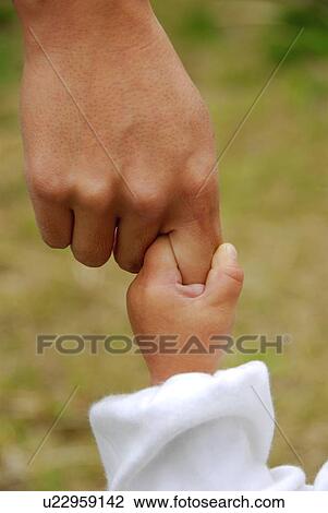 Stock Image - Baby boy holding mother's finger, close up. Fotosearch