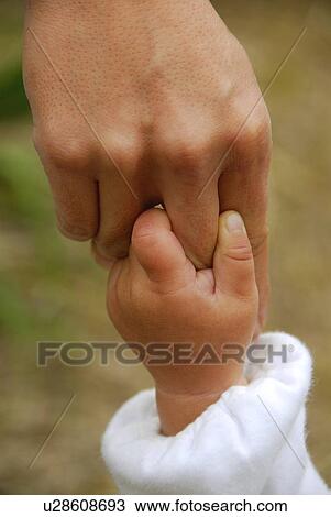 Stock Image - Baby boy holding mother's finger, close up. Fotosearch