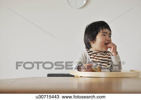 Baby boy sitting in high chair, eating bread View Large Photo Image Stock Image - Baby boy sitting in high chair, eating bread. Fotosearch