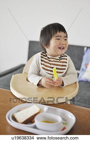 Picture - Baby boy sitting in high chair, smiling. Fotosearch