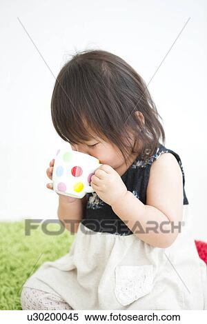 Stock Photography - Baby girl drinking from cup. Fotosearch
