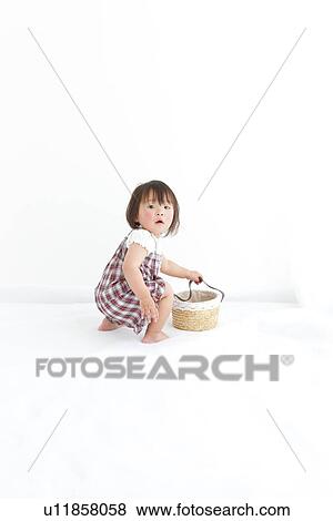 Stock Photo - Baby girl holding a basket. Fotosearch