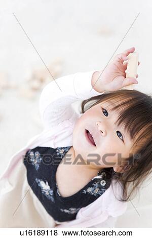 Stock Photo - Baby girl holding a wooden building block. Fotosearch