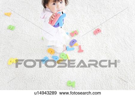 Stock Photo - Baby girl holding alphabet and number toys. Fotosearch