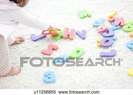 Stock Photography - Baby girl holding alphabet and number toys. Fotosearch
