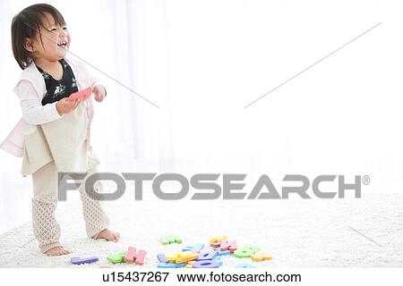 Stock Photo - Baby girl holding alphabet toy. Fotosearch