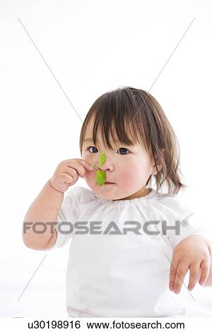 Stock Photograph - Baby girl holding sapling. Fotosearch