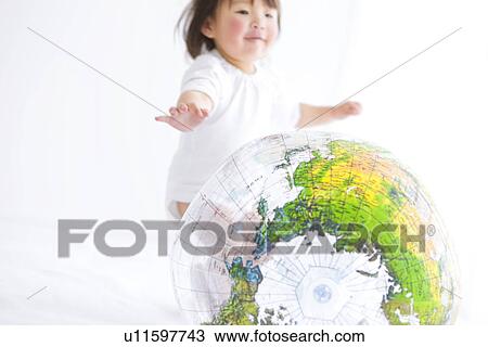 Stock Image - Baby girl playing with globe beach ball. Fotosearch