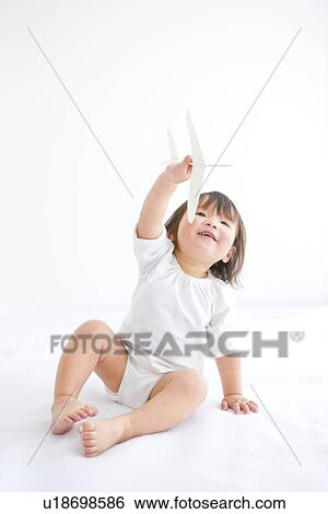 Stock Photograph - Baby girl playing with paper airplane. Fotosearch