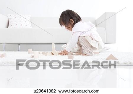Stock Image - Baby girl playing with wooden building blocks. Fotosearch
