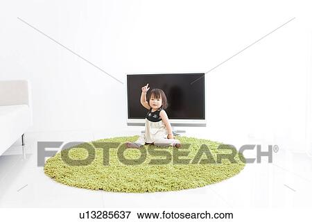 Stock Photo - Baby girl sitting in front of TV. Fotosearch