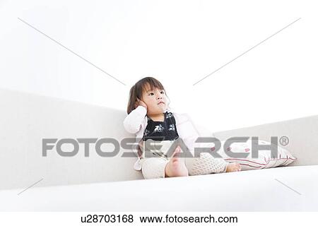 Baby girl sitting on sofa View Large Photo Image Stock Photo - Baby girl sitting on sofa. Fotosearch