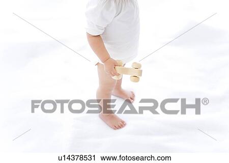 Baby girl standing and holding toy car View Large Photo Image Stock Image - Baby girl standing and holding toy car. Fotosearch