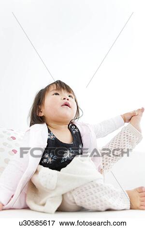 Stock Photo - Baby girl stretching on sofa. Fotosearch