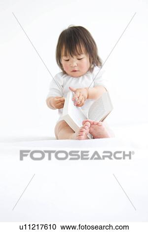 Stock Image - Baby girl turning page of book. Fotosearch