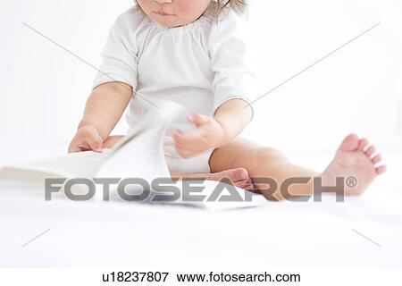 Stock Photo - Baby girl turning page of book. Fotosearch