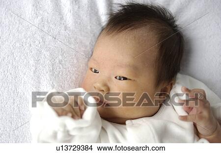Picture - Baby lying on bed, close up. Fotosearch