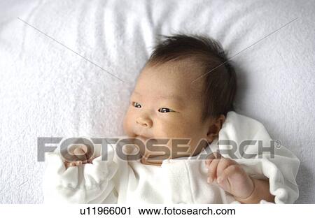 Stock Image - Baby lying on bed, close up. Fotosearch
