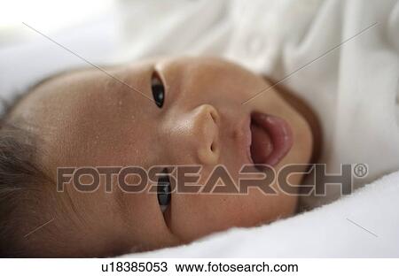 Stock Image - Baby lying on bed, close up. Fotosearch