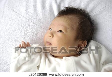 Stock Photo - Baby lying on bed, close up. Fotosearch