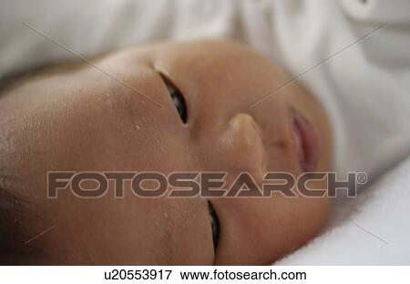 Stock Photo - Baby lying on bed, close up. Fotosearch