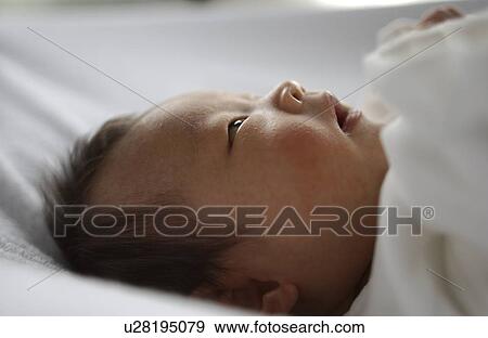 Stock Photo - Baby lying on bed, close up. Fotosearch