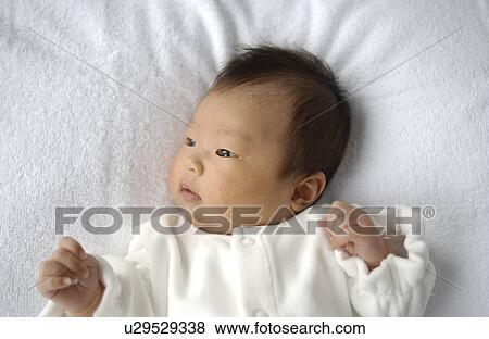 Stock Photo - Baby lying on bed, close up. Fotosearch