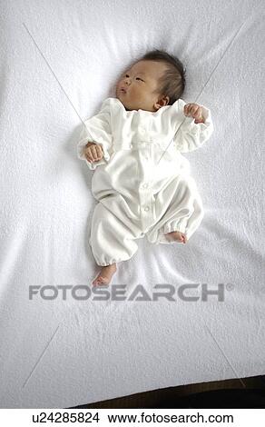 Picture - Baby lying on bed. Fotosearch