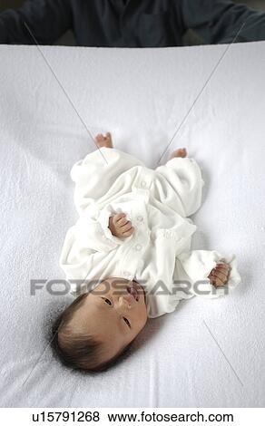 Stock Photo - Baby lying on bed. Fotosearch