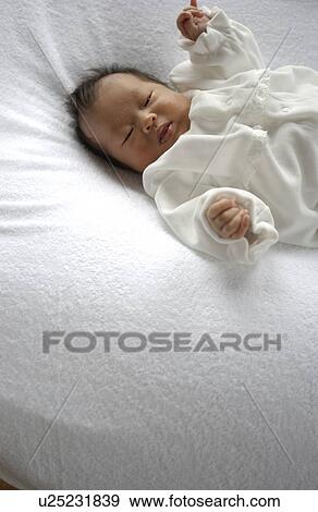 Stock Photo - Baby lying on bed. Fotosearch
