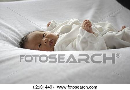 Stock Photo - Baby lying on bed. Fotosearch