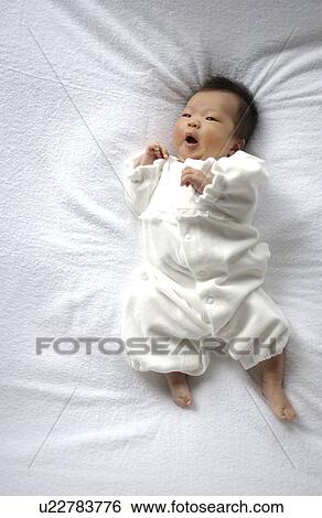 Stock Photograph - Baby lying on bed. Fotosearch
