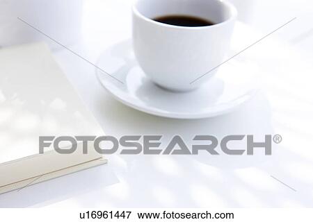 Stock Photo - Book and cup of coffee, close up, white background. Fotosearch
