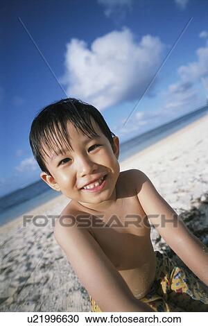 Stock Image - Boy at beach looking at camera. Fotosearch