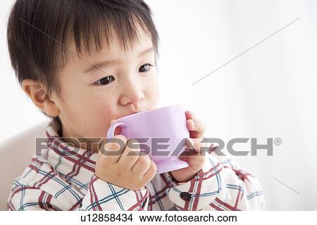 Picture - Boy drinking juice from a plastic cup. Fotosearch