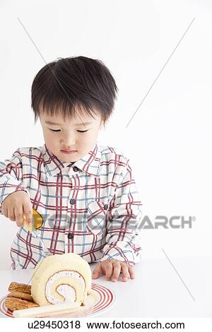 Stock Photo - Boy eating a rolled up sponge cake. Fotosearch