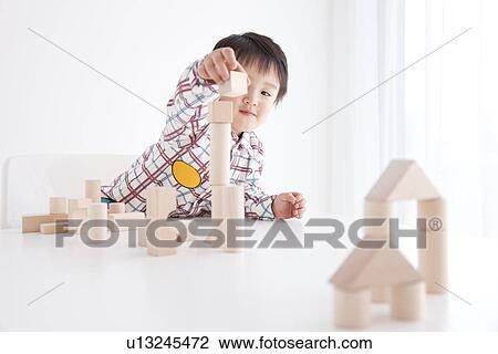 Stock Image - Boy playing with wooden building block. Fotosearch