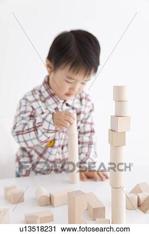 Stock Image - Boy playing with wooden building block. Fotosearch
