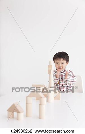 Stock Image - Boy playing with wooden building block. Fotosearch