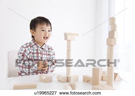 Boy playing with wooden building block View Large Photo Image Stock Photo - Boy playing with wooden building block. Fotosearch