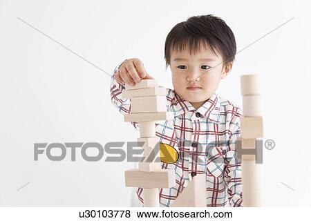 Stock Photo - Boy playing with wooden building block. Fotosearch