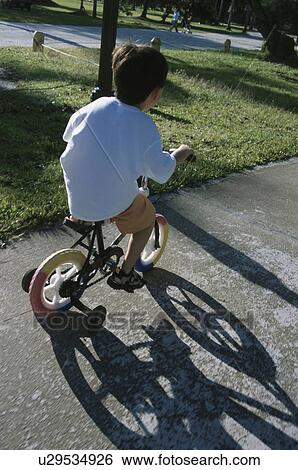 Boy riding bike with training wheels View Large Photo Image Stock Photograph - Boy riding bike with training wheels. Fotosearch