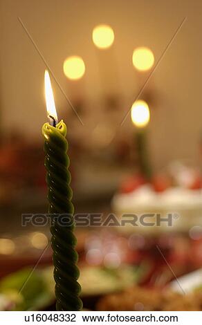 Stock Image - Burning candle, Christmas cake in background, close up, differential focus. Fotosearch