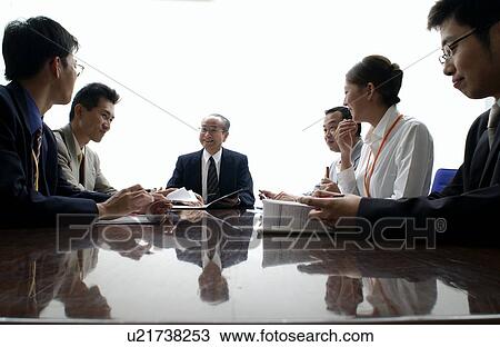 Stock Image - Business Men and Business Women at Meeting. Fotosearch