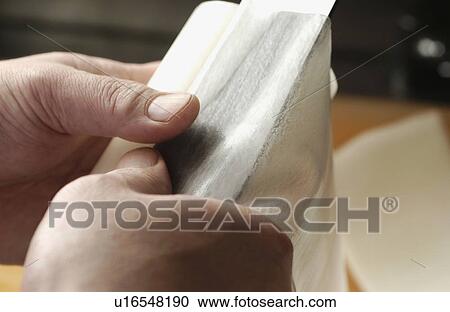 Stock Image - Chef peeling Daikon radish, close up. Fotosearch
