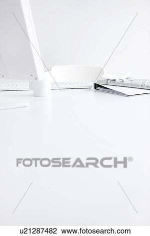 Stock Image - Computer and office supplies on desk in office, white background, copy space. Fotosearch