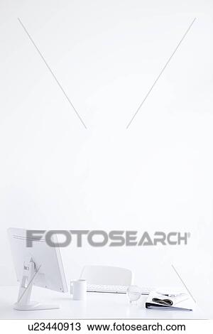 Stock Image - Computer and office supplies on desk in office, white background, copy space. Fotosearch