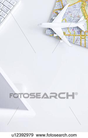 Stock Photo - Computer and toy airplane on map, white background. Fotosearch