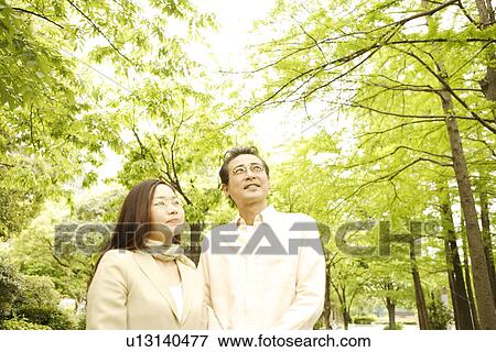 Couple standing and looking at a park View Large Photo Image Stock Photo - Couple standing and looking at a park. Fotosearch